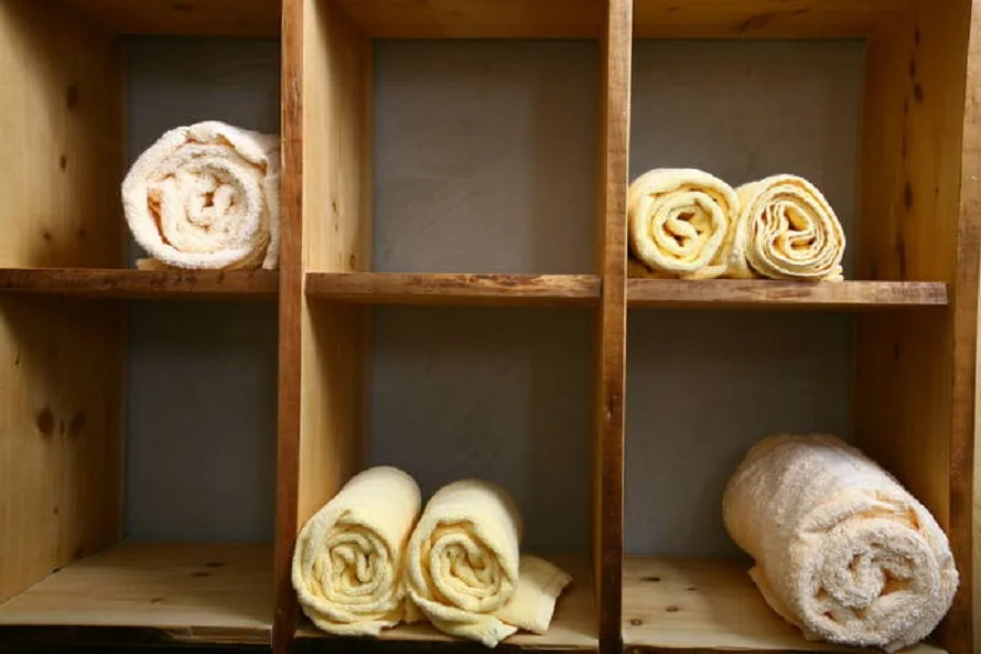 Aufgerollte Badetücher in einem Holzregal im Wellnessdörfli