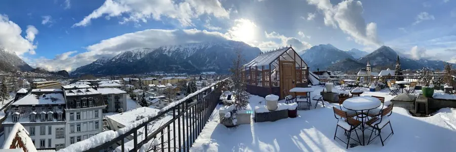 Verschneite Dachterrasse mit Pavillon, ringsum die Berge