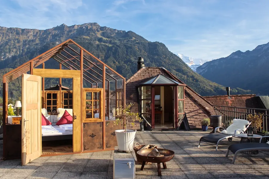 Offener Glaspavillon mit Bett auf der Dachterrasse, davor die Feuerschale