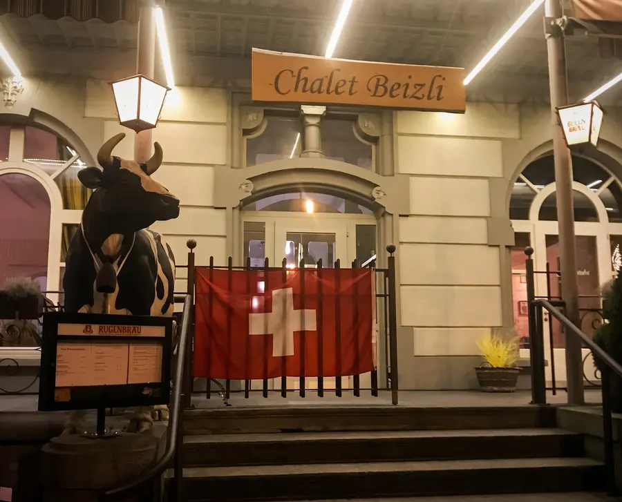 Eingang des Chalet Beizli mit Kuh und Schweizer Fahne