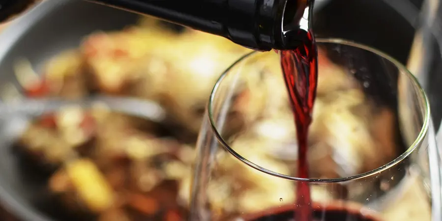 Rotwein wird in ein Glas eingeschenkt