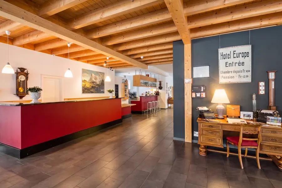 Rezeption mit Holzbalken und dem alten Schild «Hotel Europe Entrée»