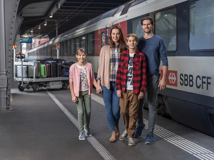 Familie mit Gepäckwagen am Bahnsteig