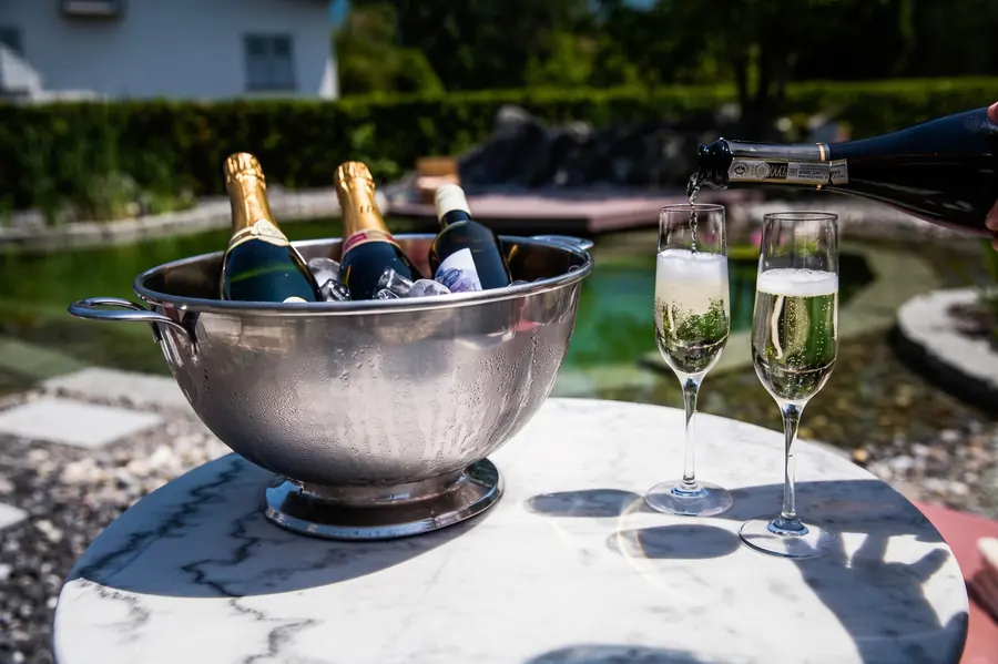 Schaumwein im Kühler und zwei Gläser im Hotelpark