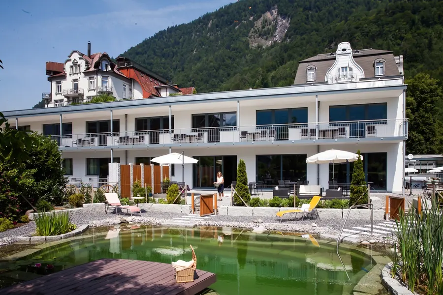 Naturbadeteich im Hotelpark, dahinter der Annex und die Berge